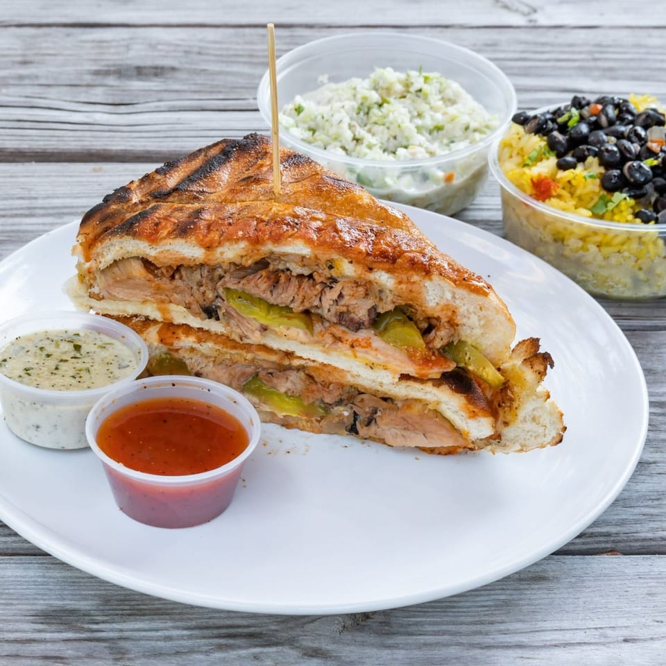 Munchies Live BBQ pulled pork sandwich with pickles, two sauces, coleslaw, and black beans with rice.