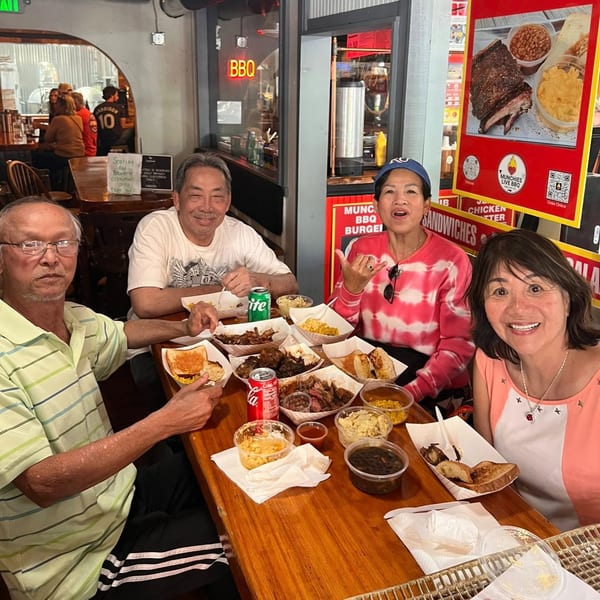 Four people enjoying a BBQ meal with various dishes and drinks at Munchies Live BBQ restaurant.