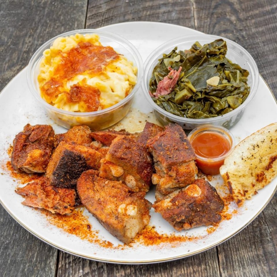 Munchies Live BBQ ribs, mac and cheese, collard greens, and cornbread on a white plate.