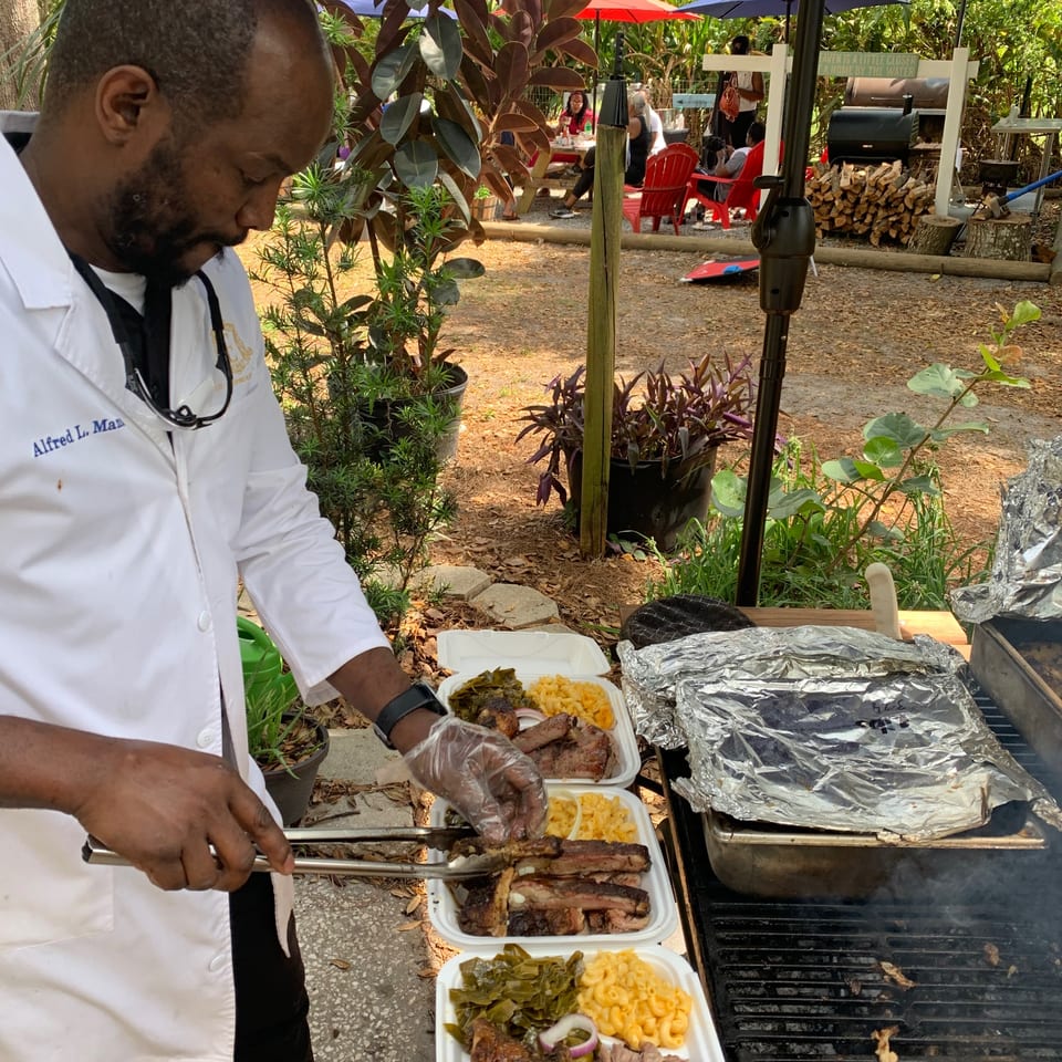 Chef Alfred L. Mar prepares BBQ ribs, collard greens, and mac and cheese in to-go containers.